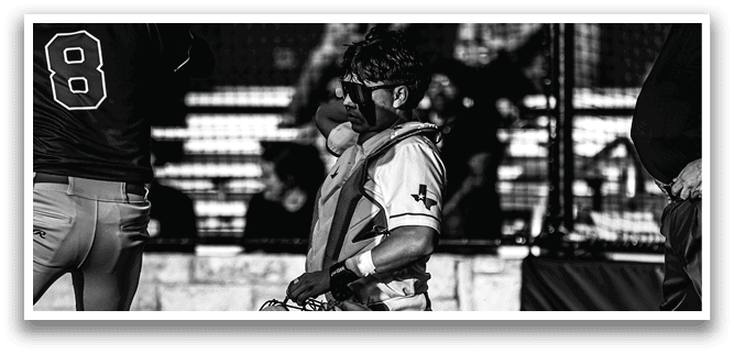 A baseball catcher kneeling on the ground with his glove on. Description generated by AI