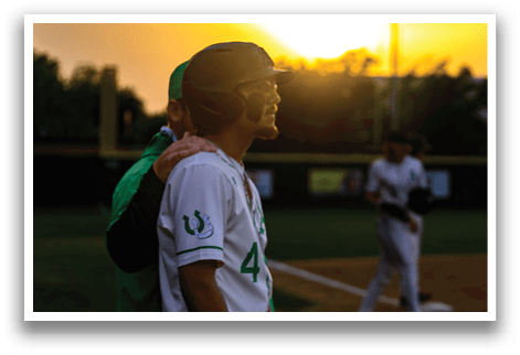 A baseball player with a green shirt and white pants. Description generated by AI