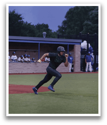 A baseball player in a green shirt and black pants is running to first base. Description generated by AI