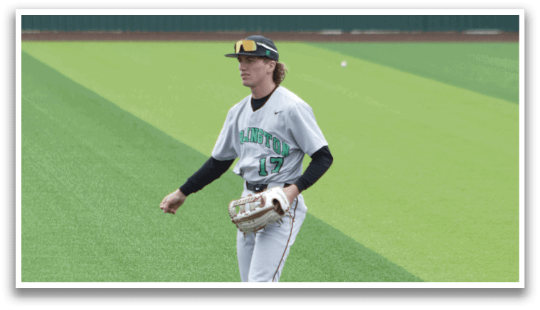 A baseball player in a grey uniform is standing on the field. Description generated by AI