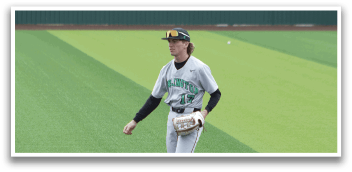 A baseball player in a grey uniform with a green logo on the front. Description generated by AI