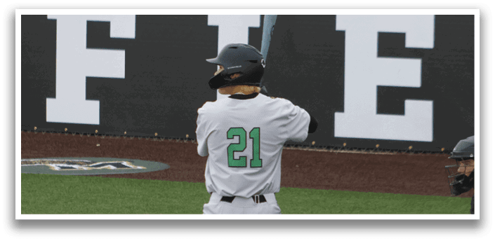 A baseball player is at bat, wearing a green and white uniform. Description generated by AI