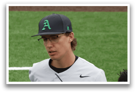 A baseball player wearing a white and green jersey. Description generated by AI