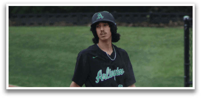 A baseball player with a black shirt and white pants standing on the field. Description generated by AI