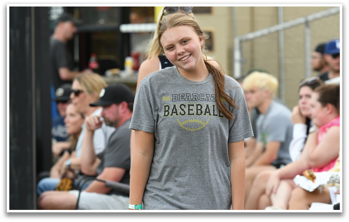A girl wearing a baseball shirt. Description generated by AI