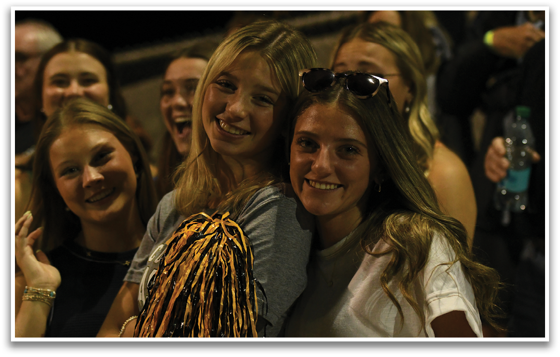 A group of cheerleaders with a large yellow and black pom pom. Description generated by AI