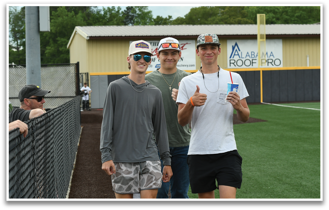 Three young men wearing sunglasses and hats are walking on a baseball field. Description generated by AI