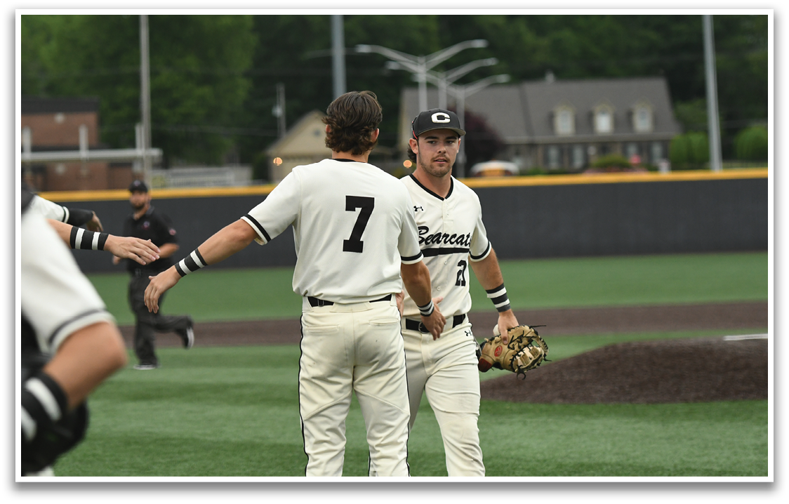 Two baseball players wearing white and black uniforms. Description generated by AI