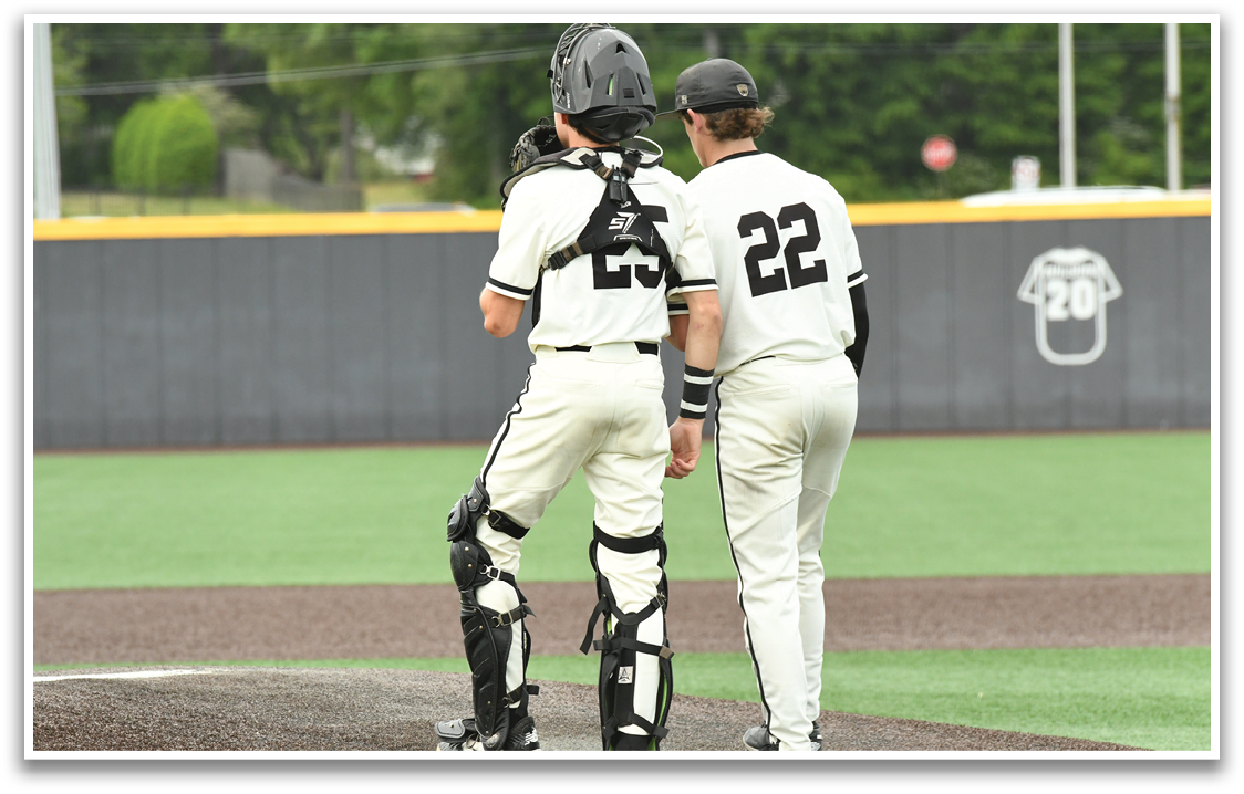 Two baseball players wearing white uniforms and black helmets. Description generated by AI