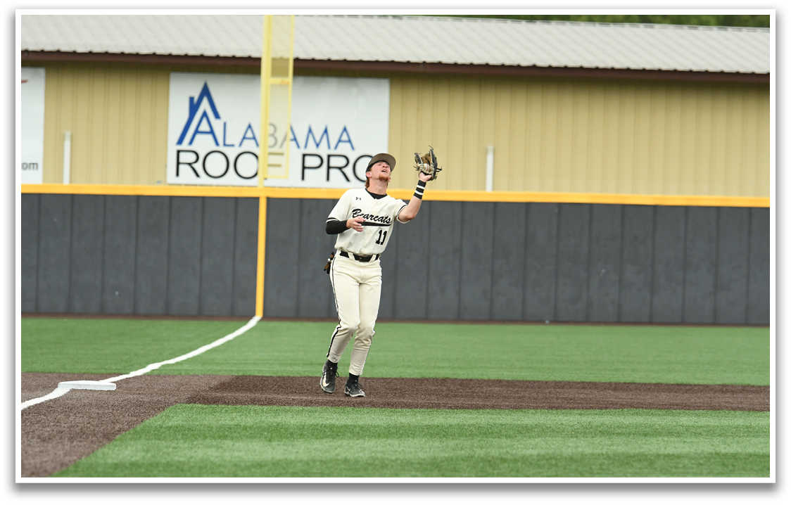 A baseball player wearing a black and white uniform is standing on a field. Description generated by AI