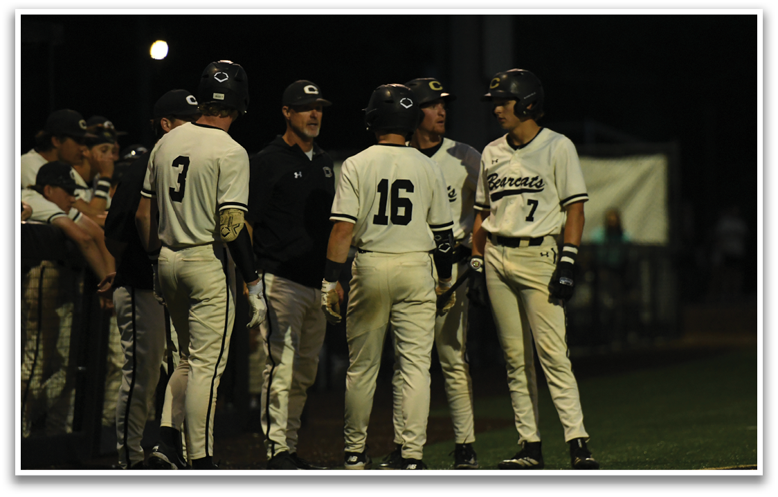 A group of baseball players wearing white uniforms. Description generated by AI
