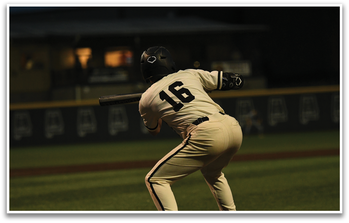 A baseball player in a white and black uniform is swinging a bat. Description generated by AI