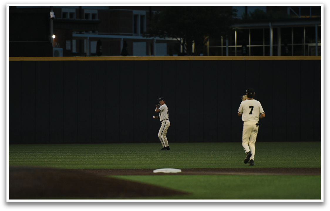 Two baseball players standing on a field. Description generated by AI