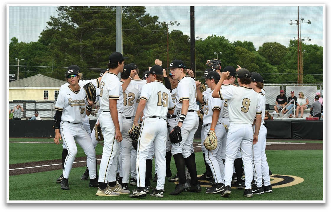 Baseball players in white uniforms huddled together. Description generated by AI