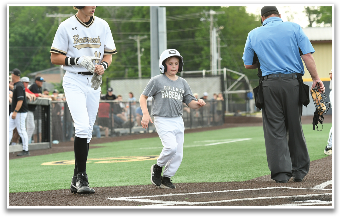 A boy in a baseball uniform is walking on a field. Description generated by AI