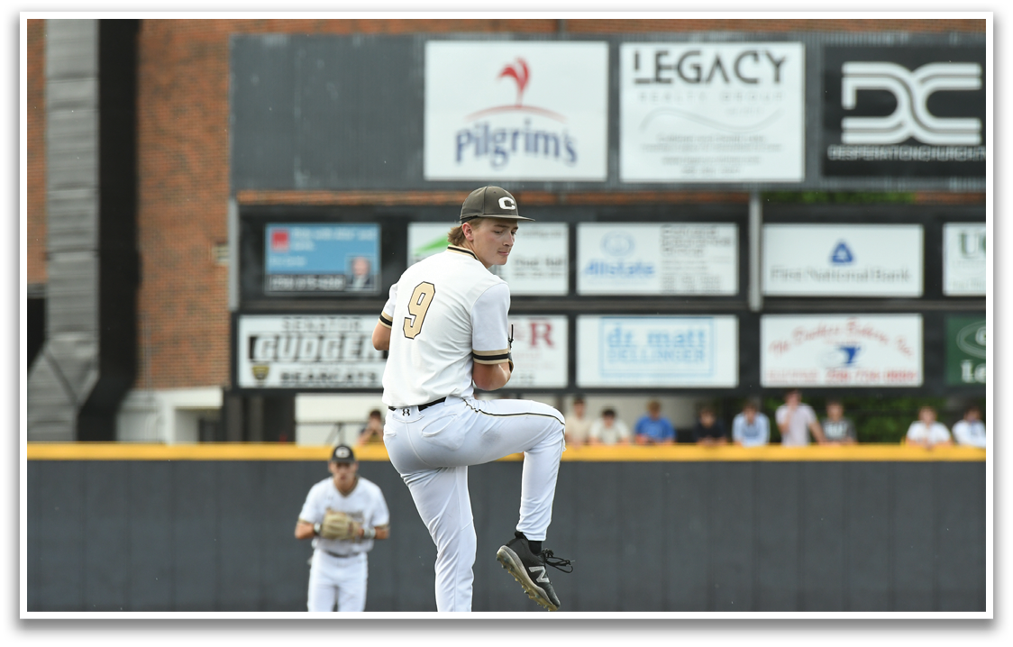 A baseball player wearing a white uniform and a black hat. Description generated by AI