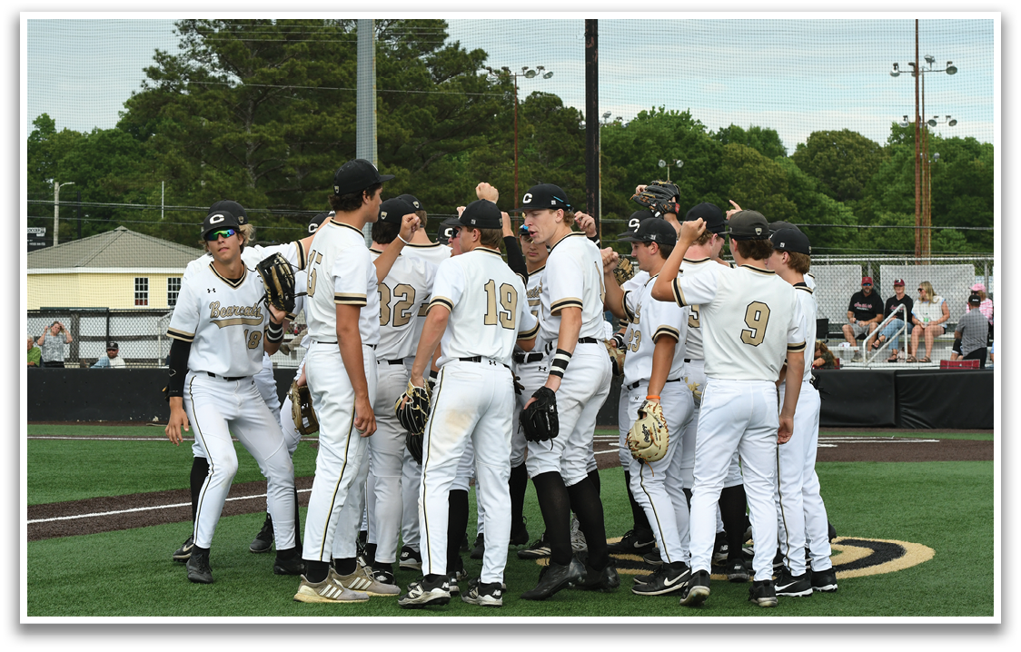 Baseball players in white uniforms huddled together. Description generated by AI
