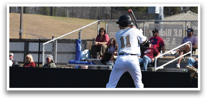 A baseball player is at bat, holding a bat and preparing to swing. The player is wearing a black and white uniform. There are several other people in the scene, some of whom are sitting on a bench and watching the game. AI generated content