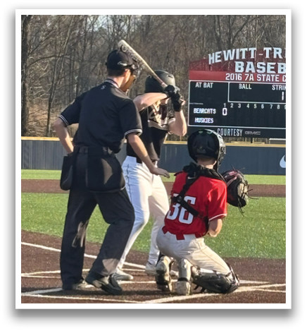 A baseball player is holding a bat, getting ready to hit the ball. The umpire and catcher are also present, preparing for the play. AI generated content