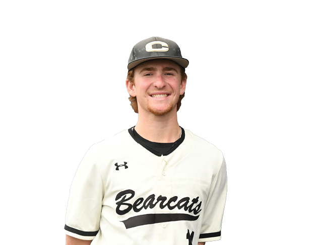 A young man wearing a white baseball uniform stands in front of a black background. AI generated content