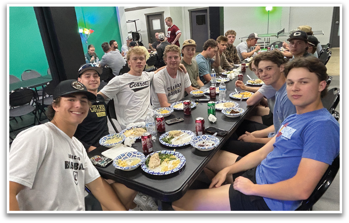 A group of young men are sitting around a table with plates of food and drinks. AI generated content