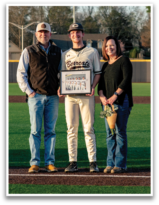 A man and woman are standing on a baseball field, posing for a picture with the man holding a framed photo. AI generated content