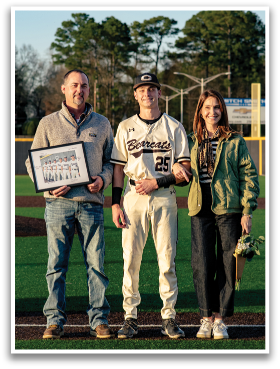 A man and woman pose for a photo with a baseball player in the middle. The man is holding a baseball bat. AI generated content