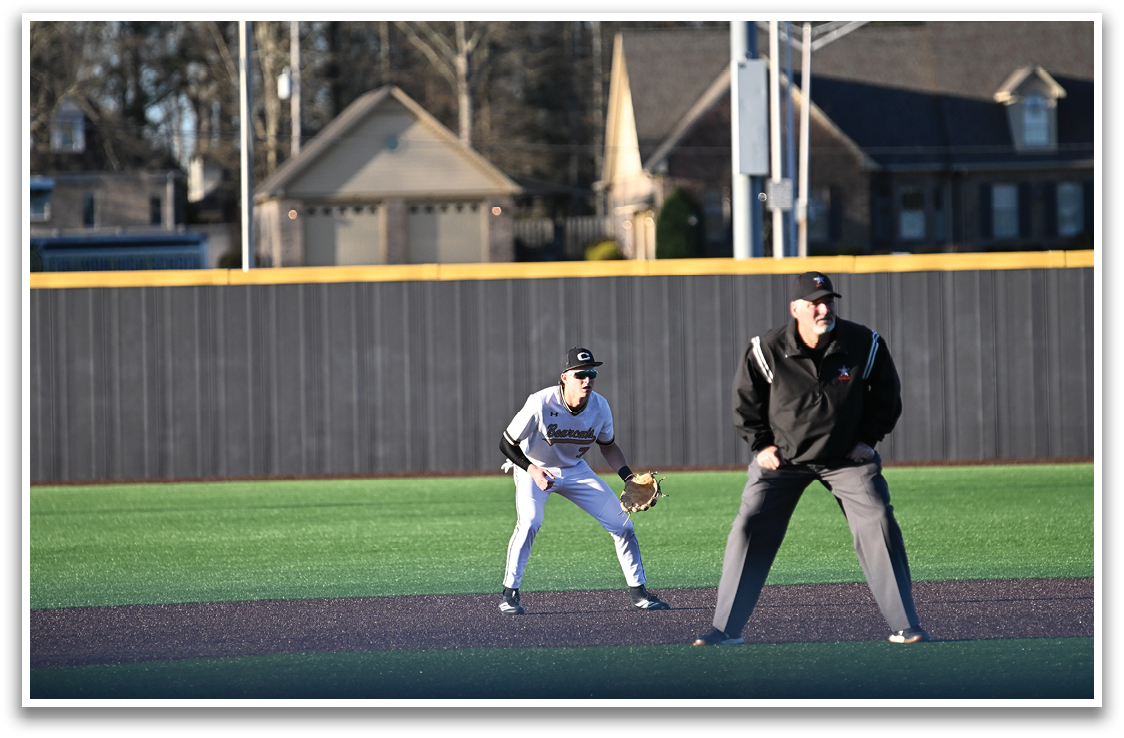 A baseball game is taking place with a man and a boy playing. The boy is wearing a baseball glove and is ready to catch the ball. The man is standing behind the boy, possibly a coach or an umpire. AI generated content