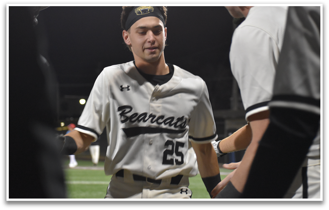 A baseball player wearing a black and white uniform with the number 25 on the back walks past another player. AI generated content