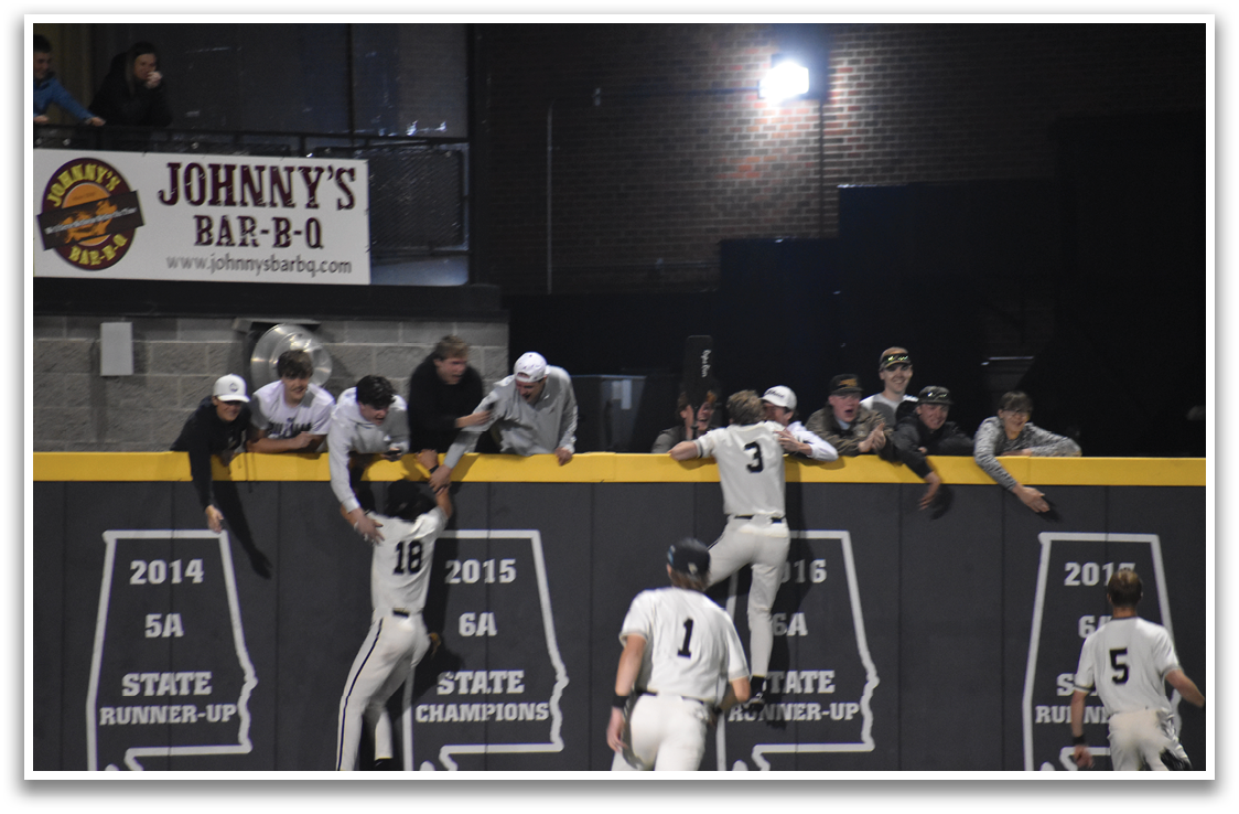 A group of people are standing on a wall, with some of them wearing baseball uniforms. AI generated content
