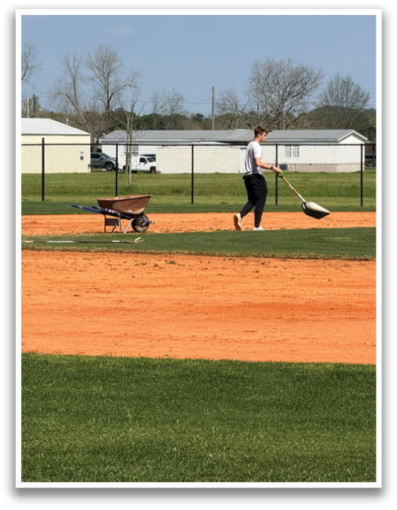 A person is holding a broom and sweeping a baseball field. AI generated content