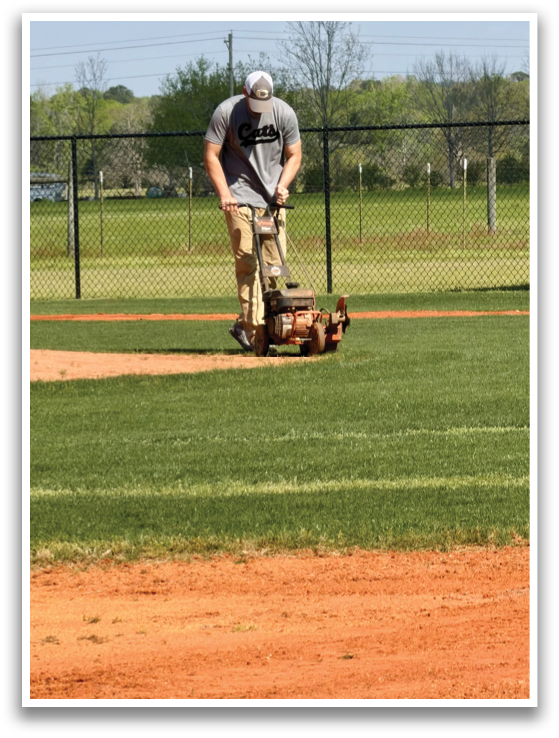 A man is mowing the grass on a baseball field. AI generated content