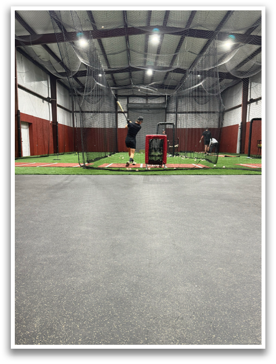 A man is standing in a batting cage, holding a baseball bat. AI generated content