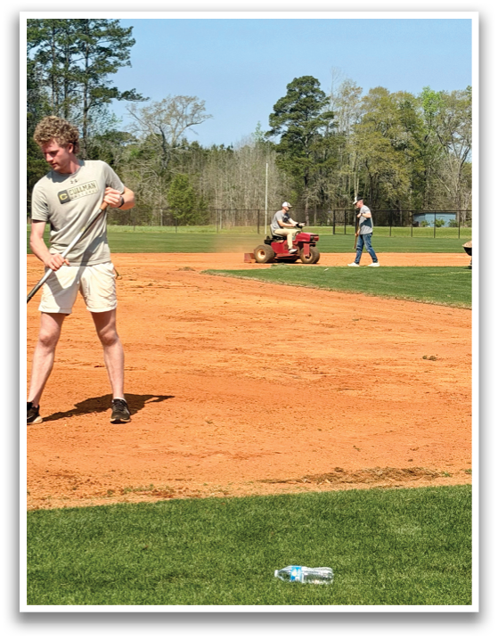 A man is standing on a baseball field, holding a bat. Another person is riding a tractor nearby. AI generated content