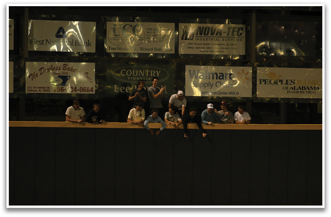 A group of people are sitting on a wall in front of a stadium. AI generated content