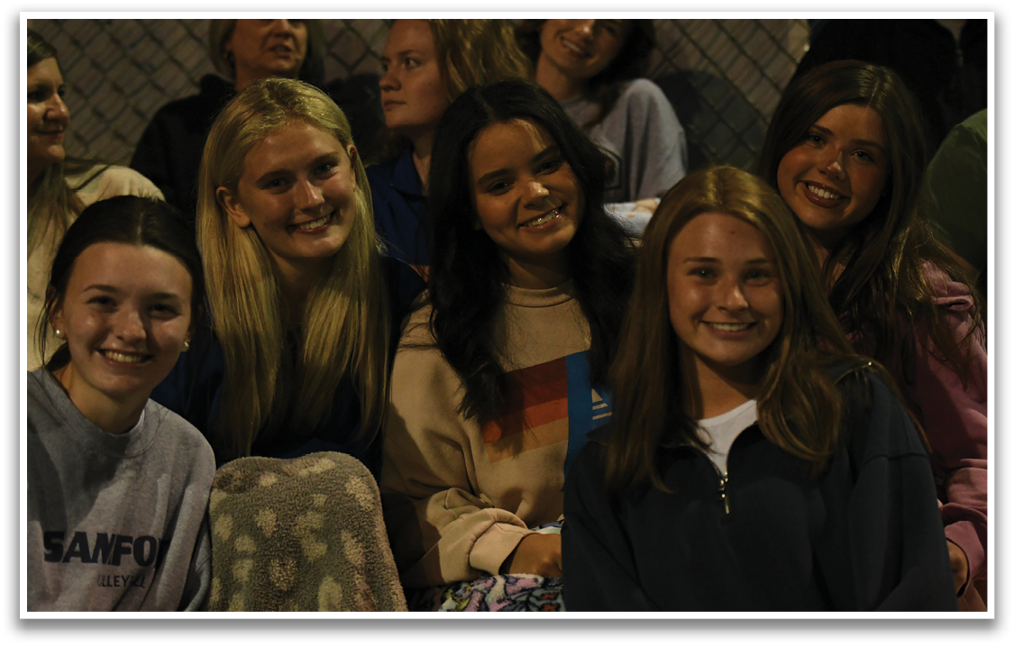 A group of women are sitting together, smiling and posing for a picture. AI generated content