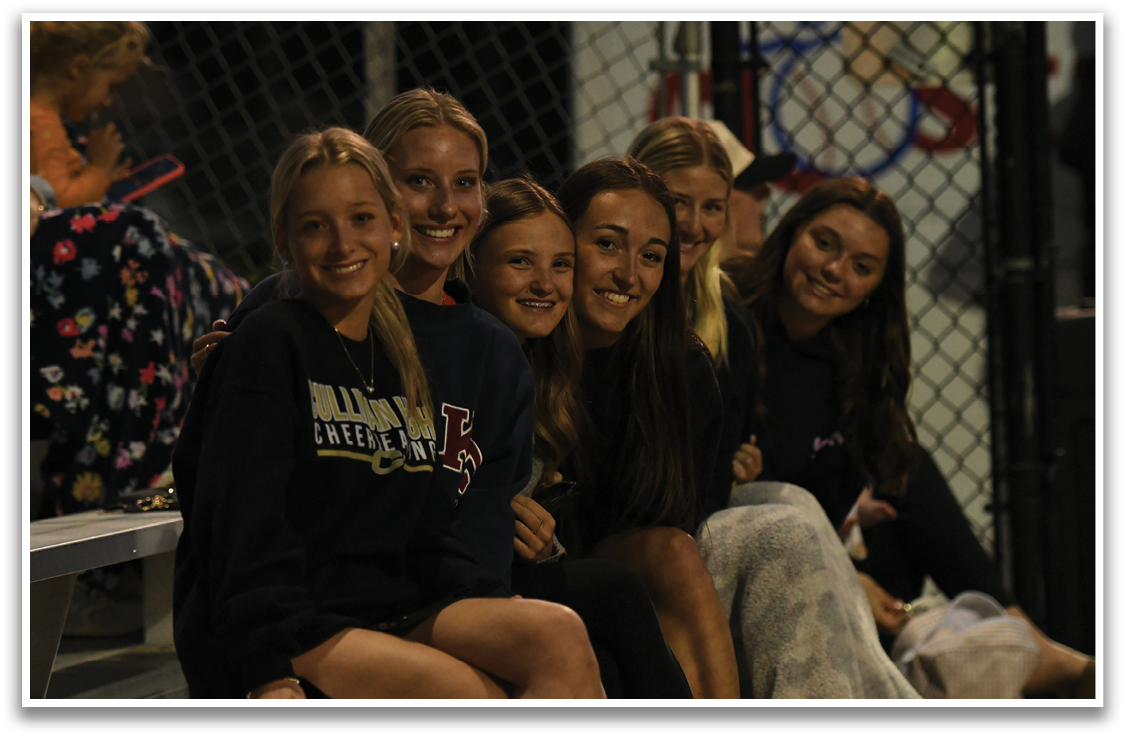 A group of girls are sitting on a bench, posing for a picture. AI generated content