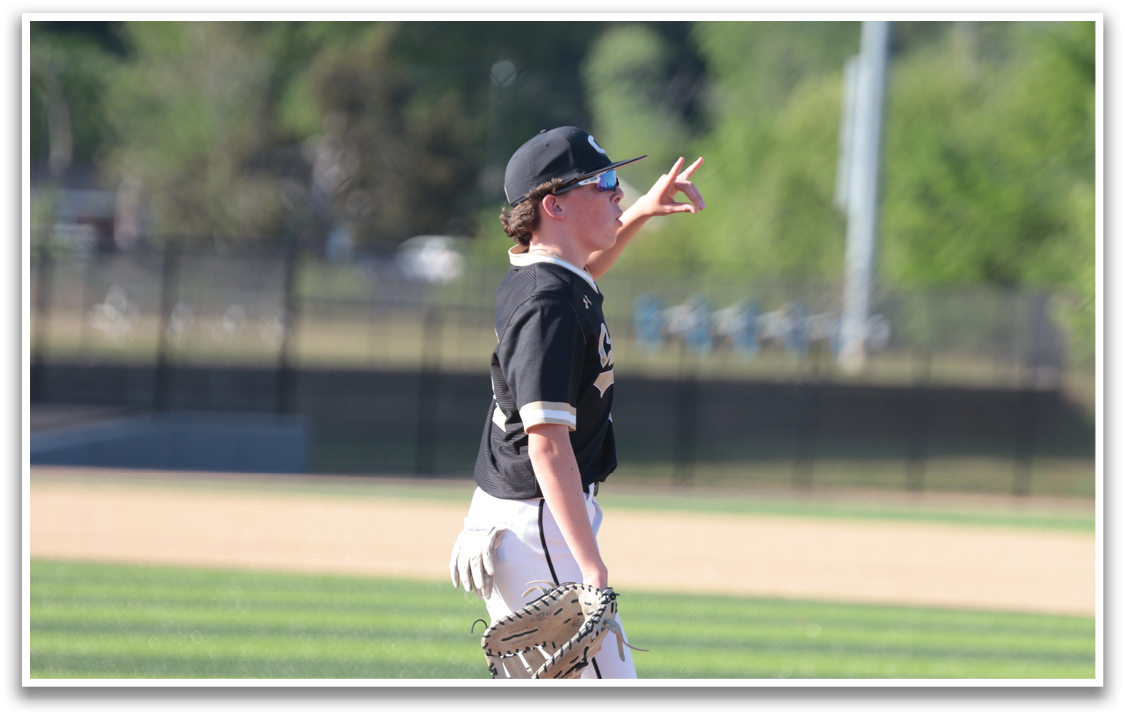 A baseball player wearing a black shirt and white pants is pointing at something in the distance. AI generated content