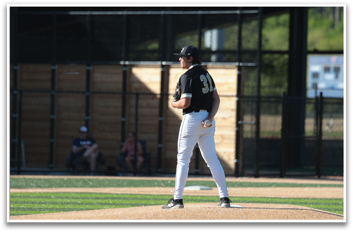 A baseball player wearing a black shirt and white pants stands on the pitcher's mound, waiting for the next play. AI generated content