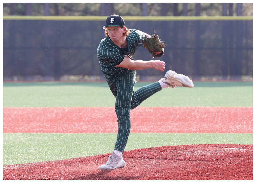 A baseball player in a green shirt and white shoes is pitching a ball. Description generated by AI