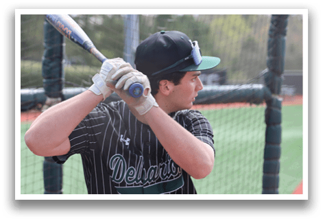 A baseball player in a black and green jersey is holding a bat and getting ready to swing. Description generated by AI