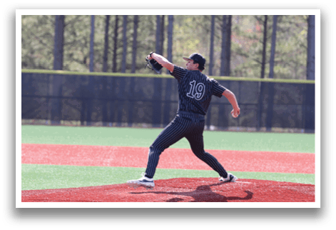 A baseball player in a black and grey uniform is pitching a ball. Description generated by AI
