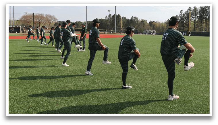 A baseball player in a green shirt and white shoes is pitching a ball. Description generated by AI