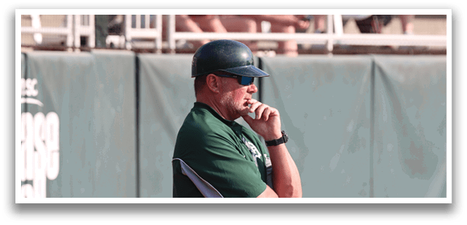A baseball coach wearing a green shirt and a hat. Description generated by AI