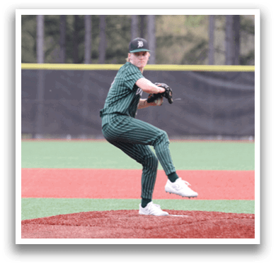 A baseball player in a green shirt and white shoes is pitching a ball. Description generated by AI
