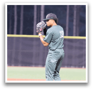 A baseball player in a green shirt and gray pants is on the mound. Description generated by AI
