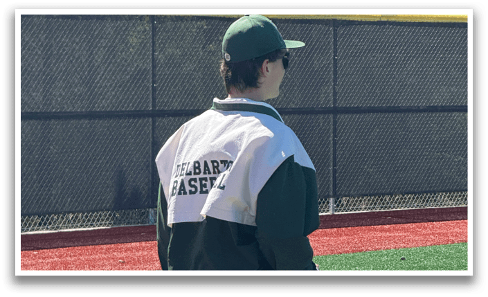 A man wearing a green and white jacket and striped pants. Description generated by AI