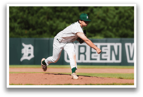 A baseball player in a black shirt and black socks is bending over to catch a ball. Description generated by AI