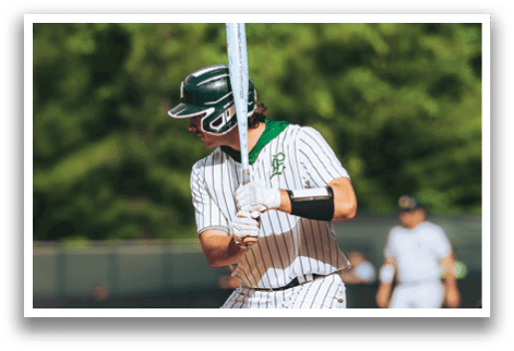 A baseball player in a black shirt and black socks is bending over to catch a ball. Description generated by AI