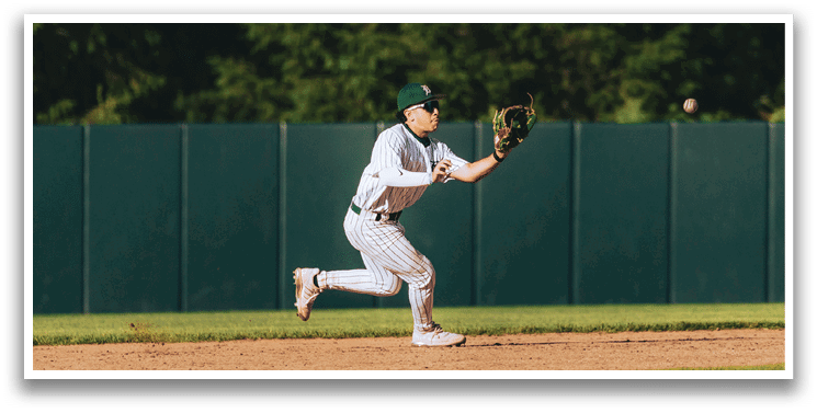 A baseball game is taking place with a man in a black shirt and gray pants standing behind a catcher. Description generated by AI
